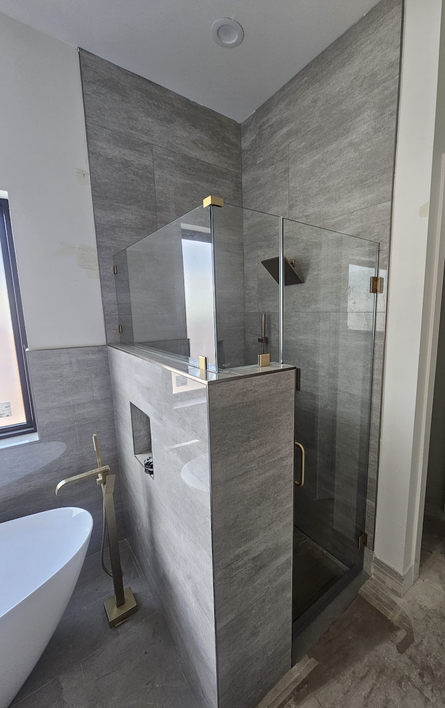 Frameless shower with brass hardware by Racso Glass LLC